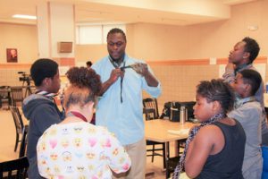 African-American man showing a group of young people how to tie a tie