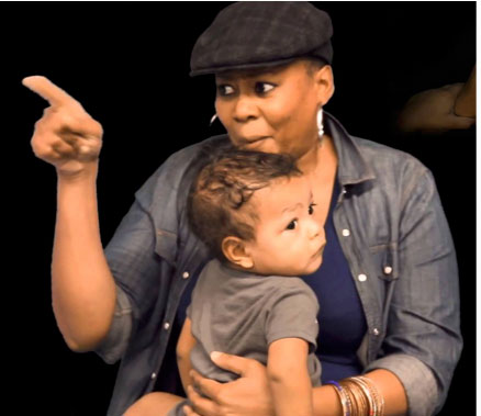 Najma Johnson sits with a toddler on her lap and points to her right